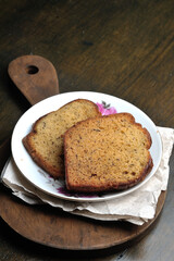 Two slices of banana bread on a small plate with a wooden chopping board