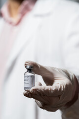 Covid 19 vaccine. Doctor or nurse or scientist with PPE (mask and gloves and gown) holding a syringe and the COVID-19 or Sars CoV 2 vaccine.