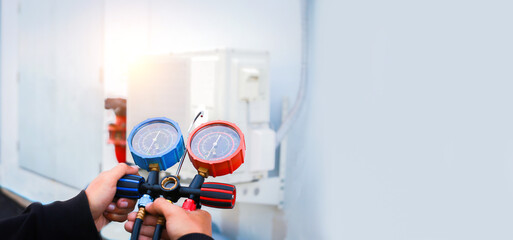 Air repair mechanic using measuring equipment for filling industrial factory air conditioners.