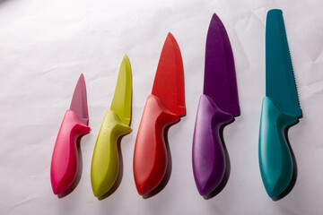 Closeup shot of colorful knives in different sizes on a white surface