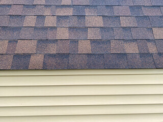 beige tan wood siding wall with new brown and black roof shingles