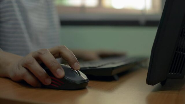 Close up woman hand scrolling wireless mouse on the computer desk. Playing game online or searching information in social network. Working with pc software apps technology concept. Work from home. 