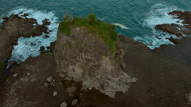 Cinematic volcanic rock beach aerial footage in Java Island, Indonesia. Taken from camera of drone flying circle
