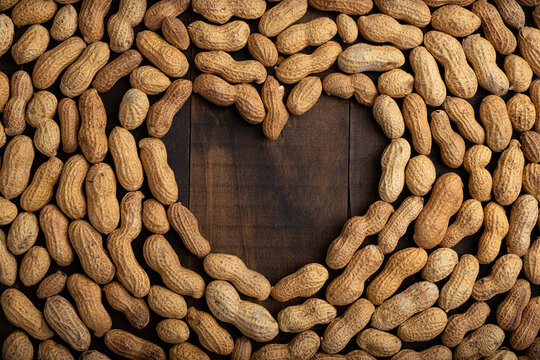 love concept image of heart shape frame made of peanuts on wooden background