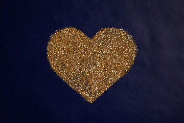 love concept image of heart shape made of golden glitter on blue paper texture background
