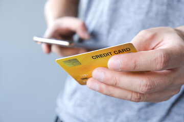 Young man sat in the living room on the sofa holding his credit card.