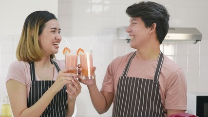 family couple husband and wife enjoying drinking fresh apple smoothie juice in kitchen