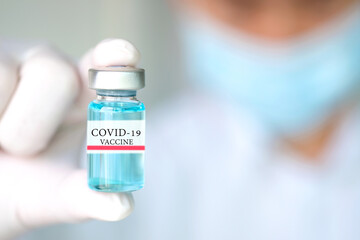 Doctor's hand holds a syringe and a blue vaccine covid19 bottle at the hospital. Health and medical concepts