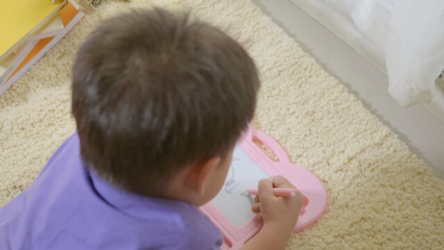 klid little boy preschool writing at the magnetic drawing board