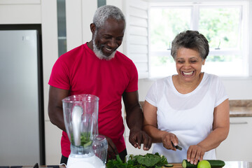 Senior african american man and woman preparing fruit and vegetable health drinks