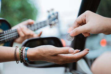 close up of busker hand receiving coin given by someone from the car on the road