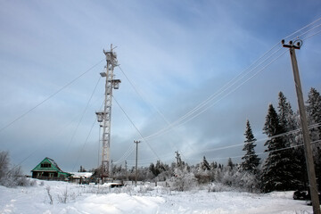 Telecommunications tower with dish and mobile antenna, in the winter forest