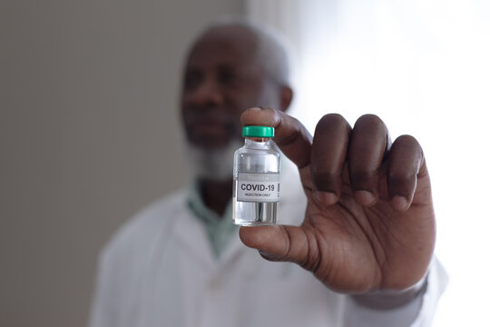Senior African American Male Doctor Holding Covid 19 Vaccine At Patients Home