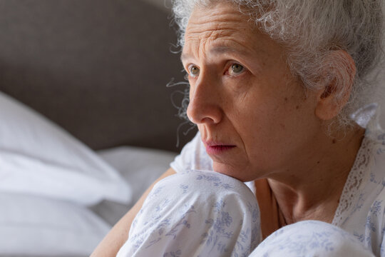 Senior caucasian woman feeling weak sitting on bed