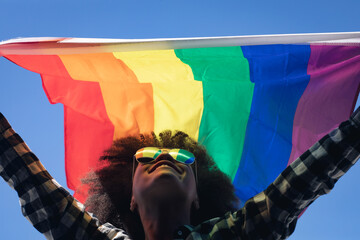 Mixed race woman standing on rooftop holding rainbow flag