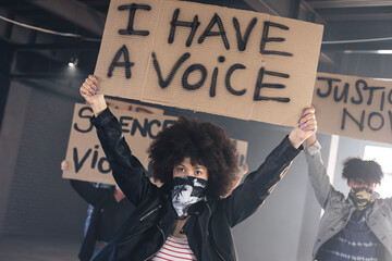 Multi ethnic group of people wearing face masks holding protest signs