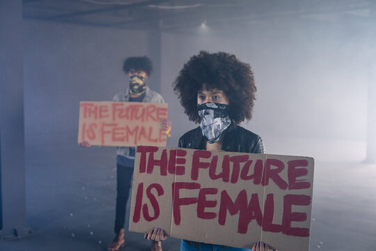 Mixed race man and woman wearing face masks holding protest signs
