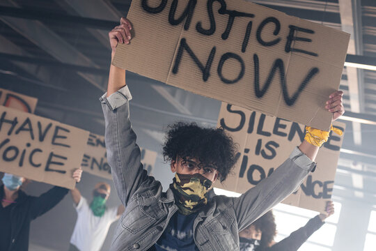 Multi ethnic group of people wearing face masks holding protest signs