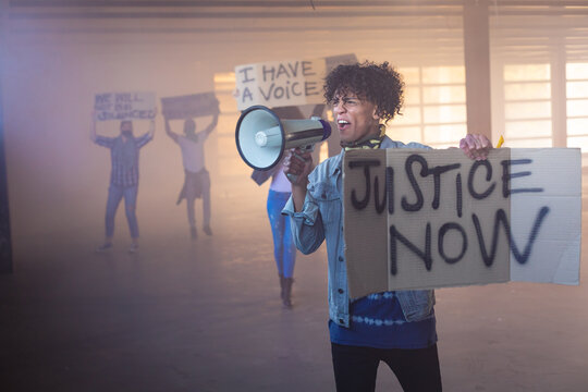 Mixed race man shouting in megaphone holding protest sign