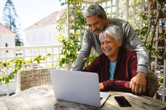Senior african american couple sitting on terrace using laptop