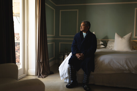 Senior african american man sitting on a bed in a sleeping room