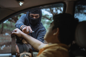 close up of man in mask using a knife while pulling the driver's bag in the afternoon