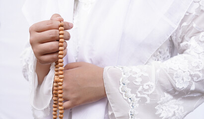 Asian muslim woman wearing prayer beads pray with tasbih in white background