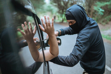 criminal robber in street holding knife near car on quiet street