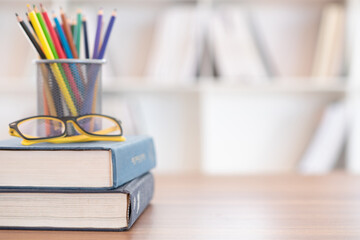 textbook stack with eyeglasses and stationary on desk in library. education concept.