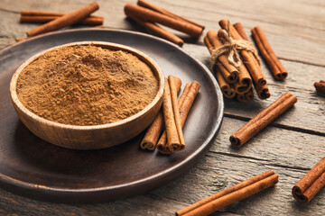 Cinnamon sticks and powder on wooden background