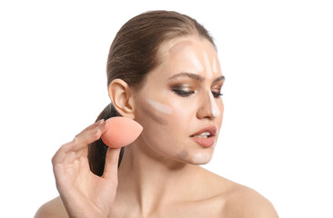 Beautiful young woman applying contouring makeup against white background