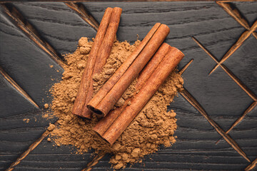 Cinnamon sticks and powder on wooden background