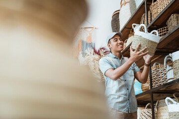 Asian man in hat holding a woven bag at a craft shop