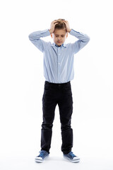 Fototapeta premium A schoolboy stands and holds his head with his hands. White background. Vertical.