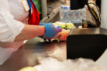 A gloved cashier in a supermarket scans the item. Close-up.