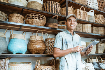 smiling young entrepreneur looking at the camera while holding a digital tablet while standing with...