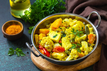 Sabji, Stewed pumpkin with soft cheese and vegetables on a dark stone table.