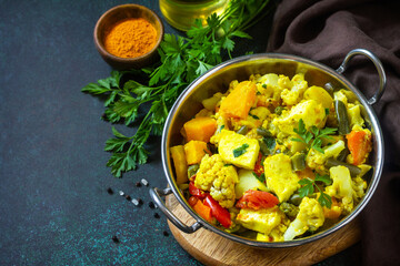 Sabji, Stewed pumpkin with soft cheese and vegetables on a dark stone table. Traditional Indian food. Copy space.
