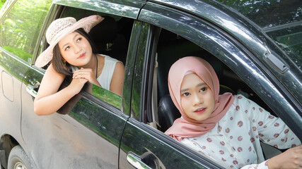 portrait of happy woman wearing hijab travelling with friend in car
