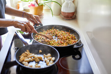 Woman cooking Spanish paella with vegetables in home