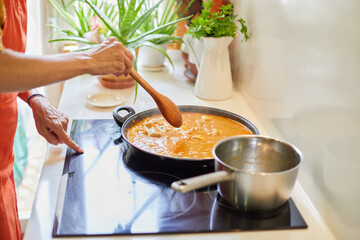 Woman hands touching ceramic hob cooking Spanish paella
