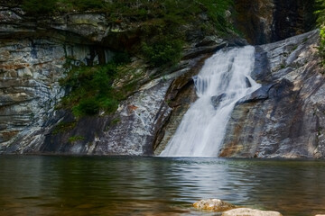 little nice waterfall over a cliff with a little lake in a forest