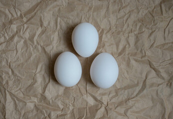 Chicken eggs are white on a background of crumpled brown craft paper.