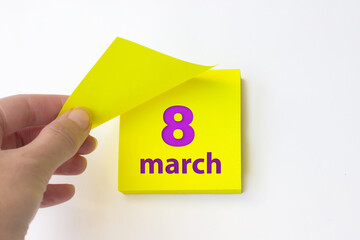 March 8th. Day 8 of month, Calendar date. Hand rips off the yellow sheet of the calendar. Spring...