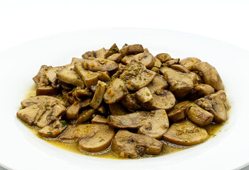 Fried mushrooms, Funghi trifolati, in a white dish isolated on white background