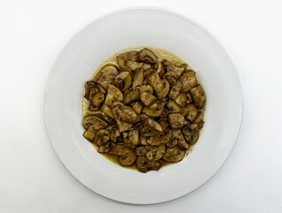 Fried mushrooms, Funghi trifolati, in a white dish isolated on white background