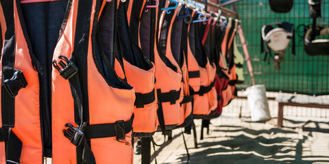 Fototapeta na wymiar Close view of bright life guard vests hangs on dryer at beach under hot sun