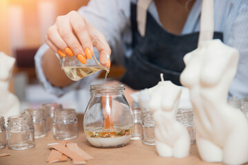 Production of scented candles from wax in silicone mold. Young woman worker in apron DIY in art studio. Concept craftswoman small business