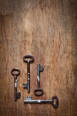 Old iron door keys lying on an old wooden surface.