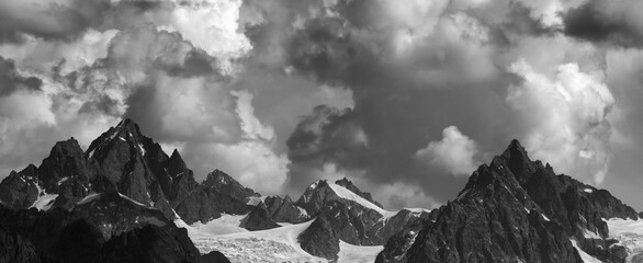 Panoramic view on high mountains with glacier and cloudy sky at summer day